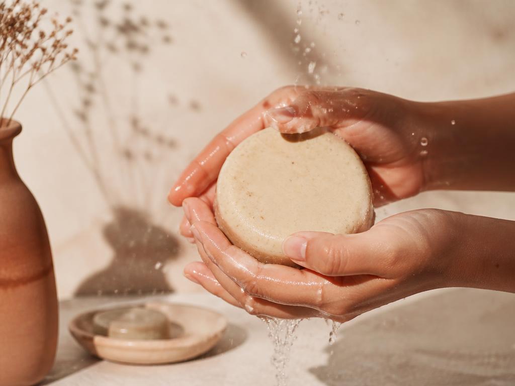 Manos sosteniendo una barra de shampoo sólido bajo el agua